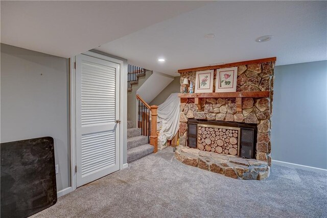 unfurnished living room featuring a stone fireplace, stairway, baseboards, carpet, and recessed lighting