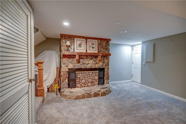 carpeted living room with baseboards, recessed lighting, and a stone fireplace