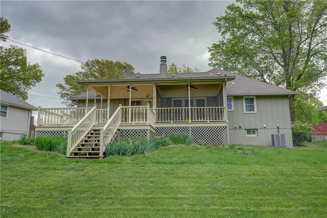 back of property with a wooden deck, a chimney, cooling unit, a ceiling fan, and a yard