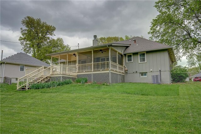 rear view of house with ceiling fan, fence, a chimney, a sunroom, and a lawn