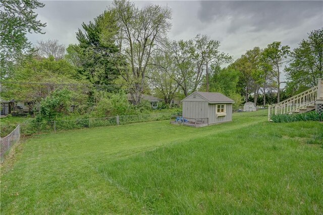 view of yard featuring an outdoor structure, fence, and a storage shed