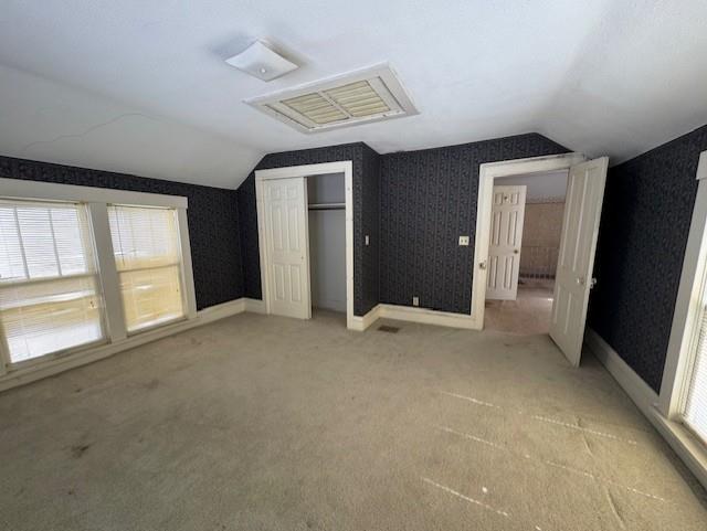 420 S Lincoln Ave, Chanute, KS 66720 - unfurnished bedroom featuring a closet, light carpet, vaulted ceiling, and multiple windows