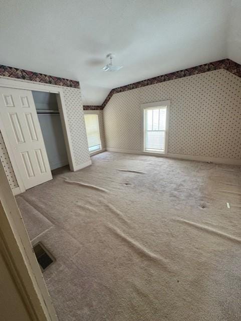 420 S Lincoln Ave, Chanute, KS 66720 - unfurnished bedroom with carpet floors, wallpapered walls, vaulted ceiling, visible vents, and a closet