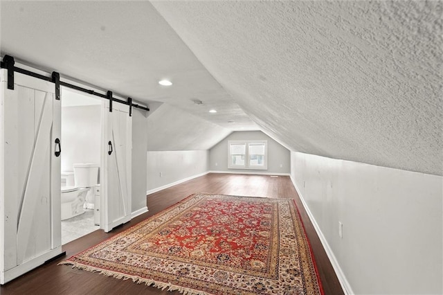 4331 Virginia Ave, Kansas City, MO 64110 - bonus room with wood finished floors, a textured ceiling, a barn door, lofted ceiling, and baseboards