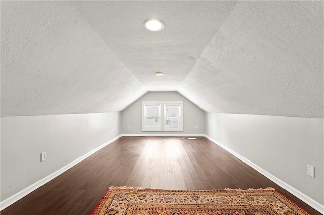 4331 Virginia Ave, Kansas City, MO 64110 - additional living space with a textured ceiling, dark wood-style floors, baseboards, and lofted ceiling