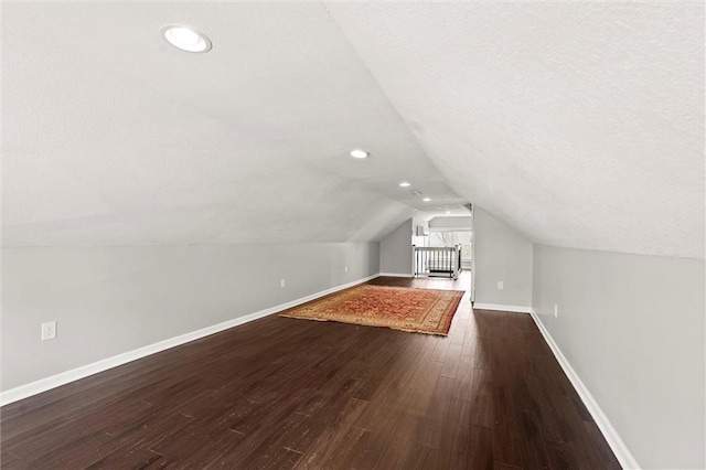 4331 Virginia Ave, Kansas City, MO 64110 - additional living space featuring dark wood-type flooring, baseboards, vaulted ceiling, a textured ceiling, and recessed lighting