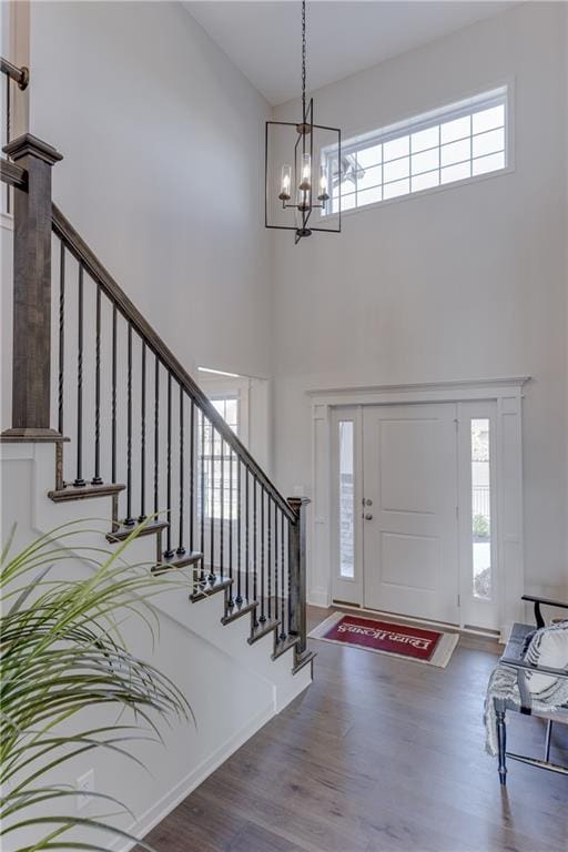 foyer featuring a notable chandelier, a healthy amount of sunlight, stairway, and a towering ceiling