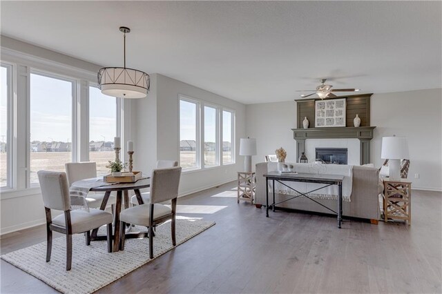 dining area with a ceiling fan, baseboards, and a large fireplace