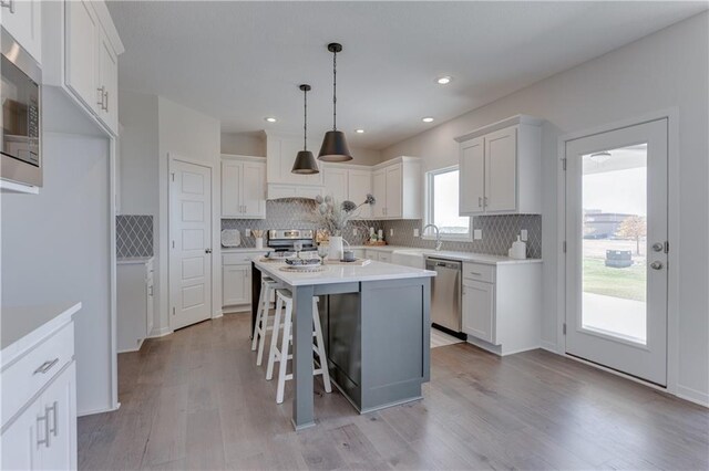 kitchen with a kitchen island, appliances with stainless steel finishes, a sink, and tasteful backsplash