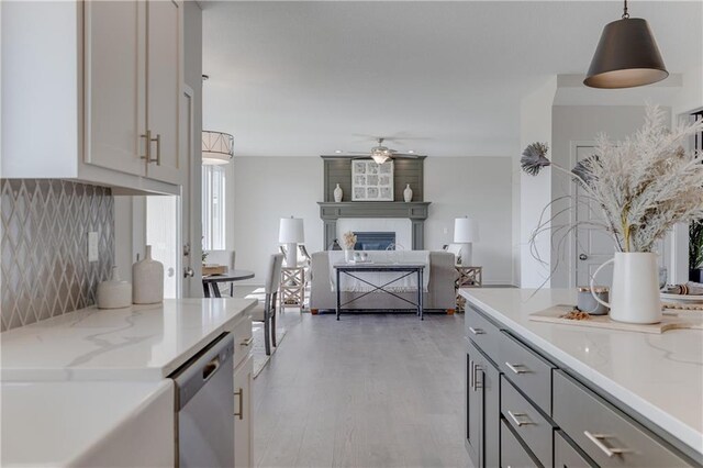 kitchen with ceiling fan, light stone counters, light wood-style floors, dishwasher, and gray cabinetry
