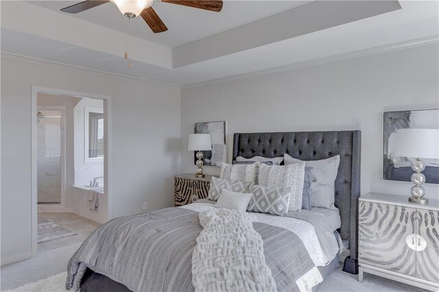 carpeted bedroom with ornamental molding, ensuite bathroom, a tray ceiling, and ceiling fan