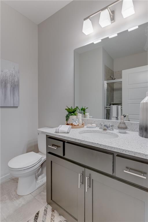 bathroom featuring vanity, baseboards, a stall shower, and toilet
