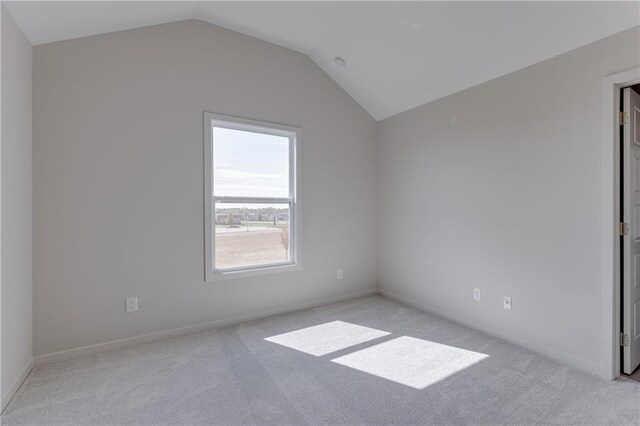 interior space featuring baseboards, vaulted ceiling, and light carpet