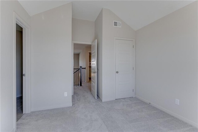 empty room featuring visible vents, baseboards, carpet floors, and lofted ceiling