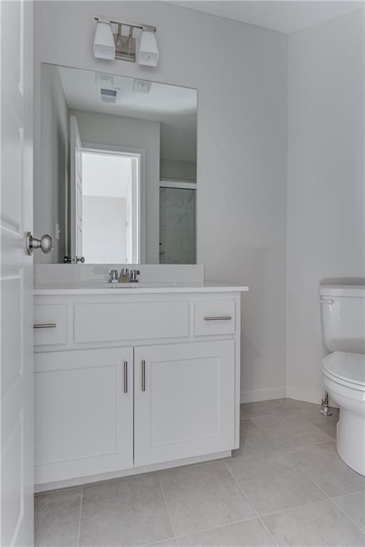 full bath with tile patterned flooring, a shower with shower door, vanity, baseboards, and toilet