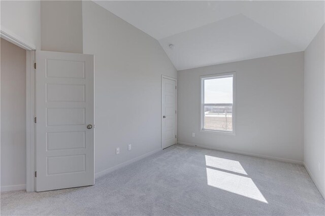 unfurnished bedroom with baseboards, carpet, and vaulted ceiling