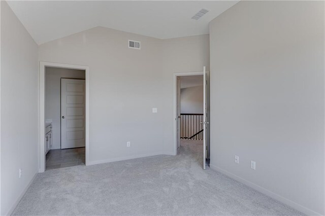 unfurnished bedroom featuring carpet flooring, baseboards, visible vents, and vaulted ceiling