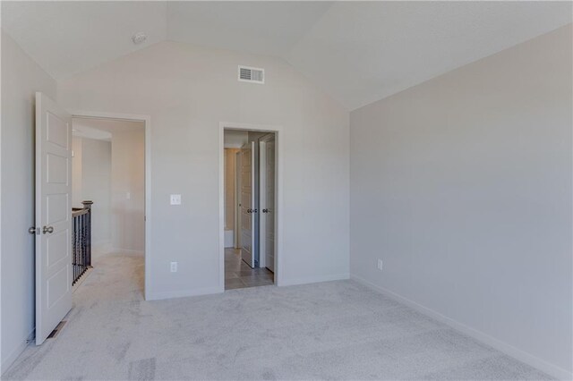 unfurnished bedroom with baseboards, visible vents, lofted ceiling, and carpet