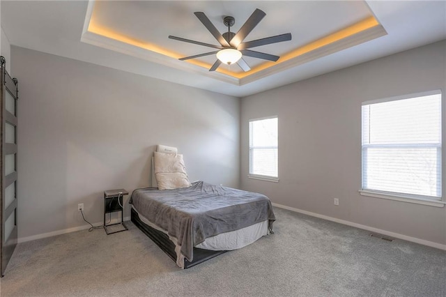 3525 S Woodland Ct, Independence, MO 64052 - carpeted bedroom with visible vents, baseboards, ceiling fan, a barn door, and a raised ceiling