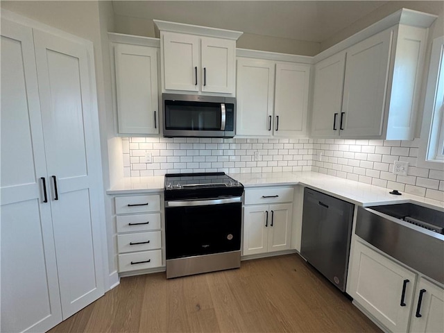 15610 Sheridan Ct, Basehor, KS 66007 - kitchen with appliances with stainless steel finishes, wood finished floors, light countertops, and white cabinets