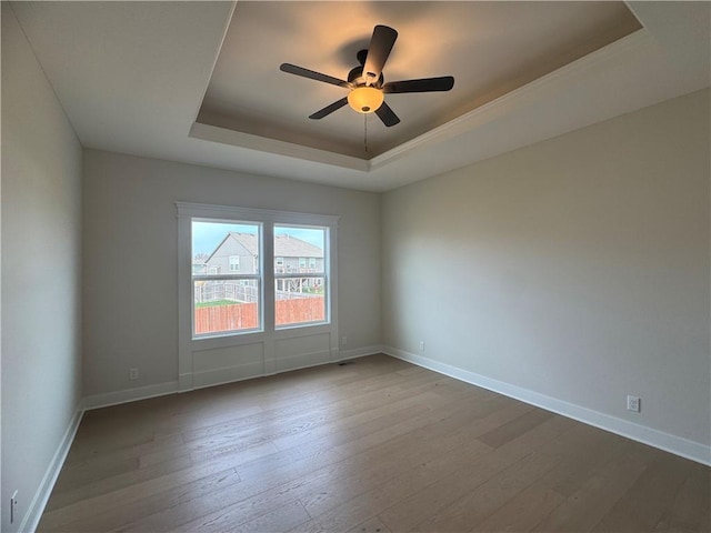 15610 Sheridan Ct, Basehor, KS 66007 - spare room featuring a raised ceiling, dark wood-style floors, ceiling fan, and baseboards