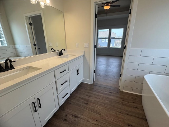 15610 Sheridan Ct, Basehor, KS 66007 - bathroom featuring double vanity, a soaking tub, wood finished floors, tile walls, and a ceiling fan