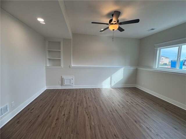 15610 Sheridan Ct, Basehor, KS 66007 - spare room featuring dark wood-type flooring, ceiling fan, baseboards, and built in shelves