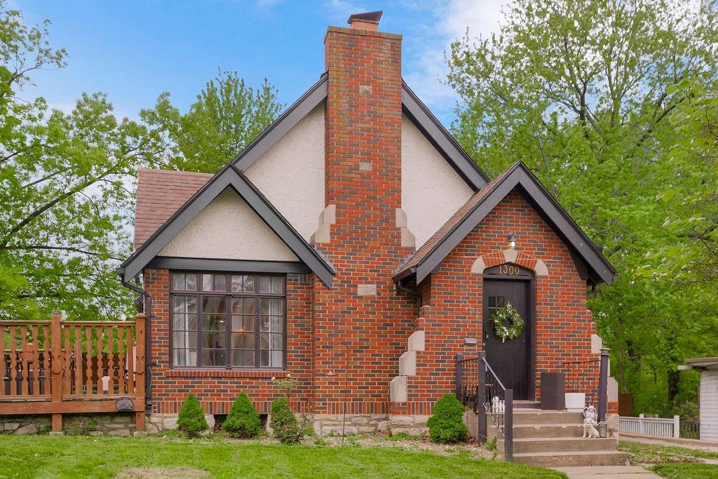 english style home featuring a chimney, stucco siding, and brick siding