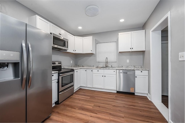 1001 Kickapoo St, Leavenworth, KS 66048 - kitchen with appliances with stainless steel finishes, a sink, white cabinets, dark wood-type flooring, and recessed lighting