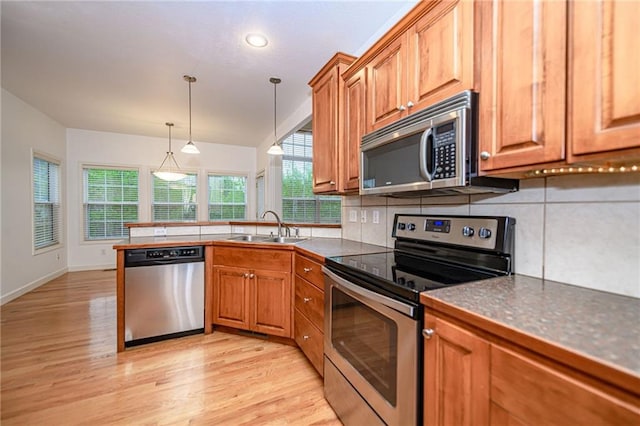 2500 Gabrianna Ct, Columbia, MO 65203 - kitchen featuring appliances with stainless steel finishes, a sink, brown cabinetry, light wood-style flooring, and a peninsula