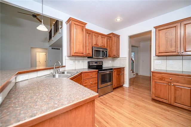 2500 Gabrianna Ct, Columbia, MO 65203 - kitchen featuring brown cabinetry, backsplash, a sink, stainless steel appliances, and light wood-style flooring