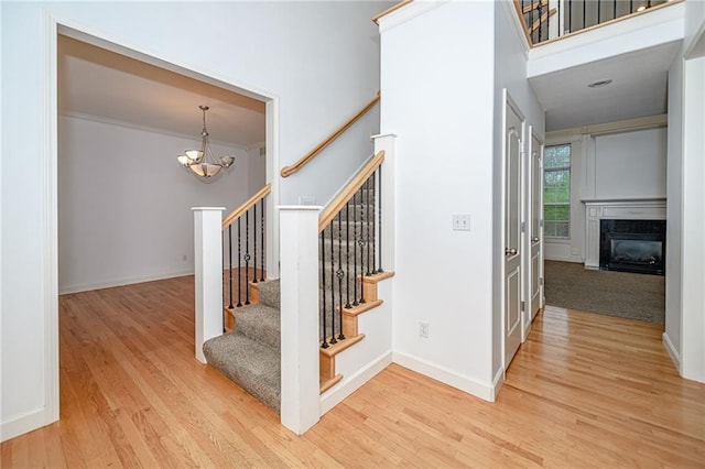 2500 Gabrianna Ct, Columbia, MO 65203 - staircase featuring a notable chandelier, baseboards, wood finished floors, a high end fireplace, and a towering ceiling