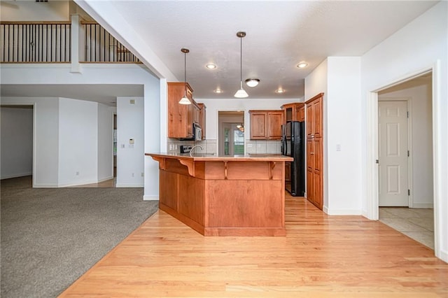 2500 Gabrianna Ct, Columbia, MO 65203 - kitchen with a breakfast bar area, brown cabinetry, freestanding refrigerator, a peninsula, and baseboards