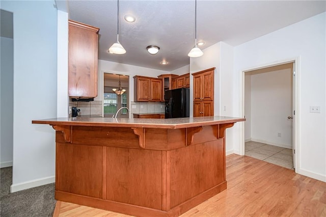 2500 Gabrianna Ct, Columbia, MO 65203 - kitchen featuring a breakfast bar area, a peninsula, brown cabinetry, and black fridge