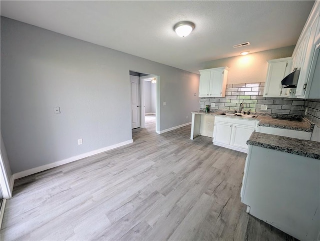 597 SE 110th St, Warrensburg, MO 64093 - kitchen with decorative backsplash, baseboards, white cabinetry, under cabinet range hood, and a sink