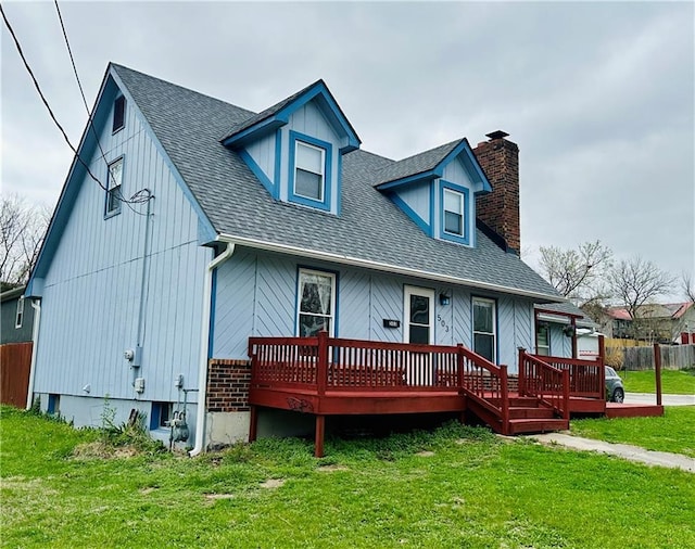 view of front facade featuring a chimney, a front yard, roof with shingles, a wooden deck, and fence