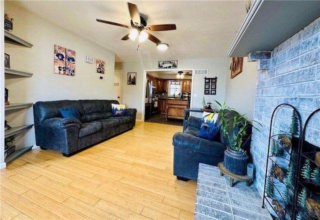 living room with visible vents, a ceiling fan, and light wood finished floors
