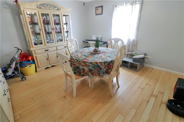 dining space featuring baseboards, light wood finished floors, and a healthy amount of sunlight