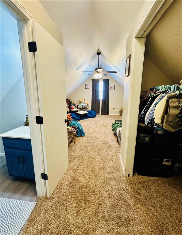 interior space with carpet flooring, a ceiling fan, and lofted ceiling