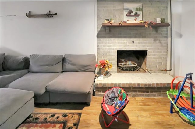 living room featuring a brick fireplace and wood finished floors
