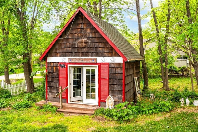 view of outdoor structure with fence and an outbuilding