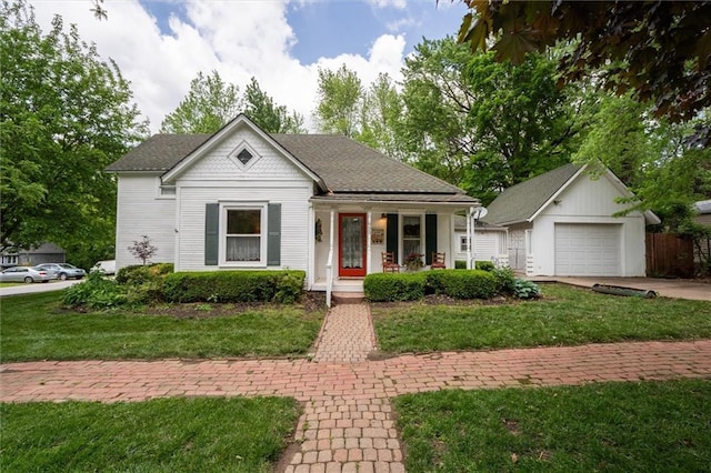 view of front of house featuring a porch, a front yard, concrete driveway, and a detached garage