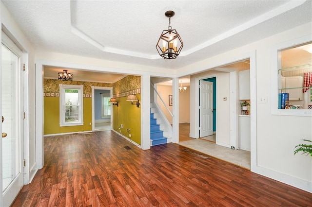 empty room featuring a chandelier, stairs, wood finished floors, and a textured ceiling