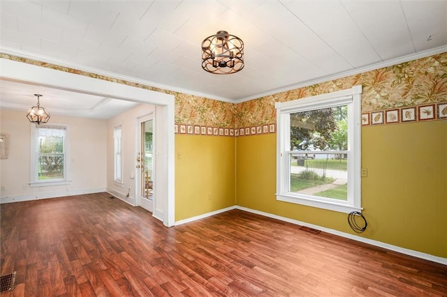 empty room with a chandelier, wood finished floors, healthy amount of natural light, and baseboards