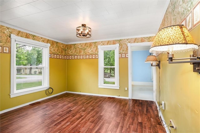 unfurnished dining area featuring wood finished floors, crown molding, and baseboards