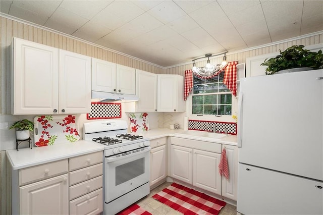 kitchen with white appliances, under cabinet range hood, crown molding, light countertops, and white cabinets