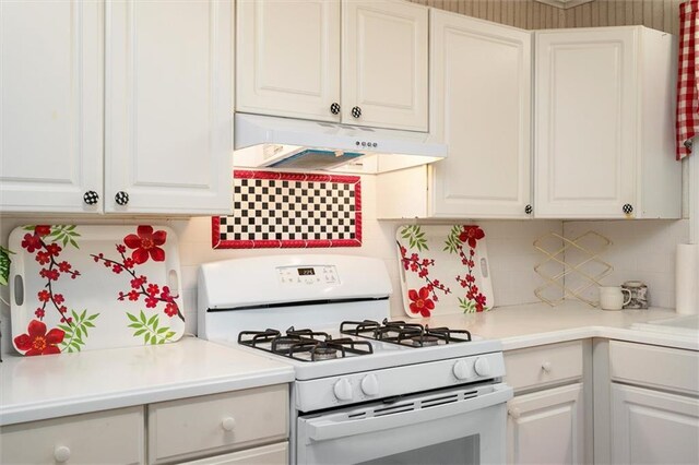 kitchen featuring white gas range, under cabinet range hood, white cabinetry, tasteful backsplash, and light countertops