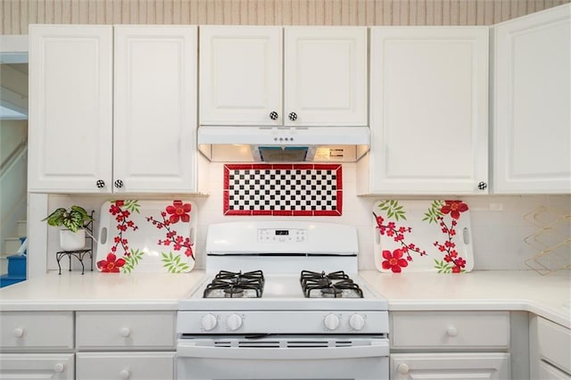 kitchen featuring white gas stove, under cabinet range hood, white cabinets, decorative backsplash, and wallpapered walls