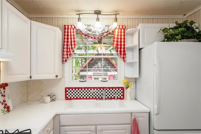 kitchen with freestanding refrigerator, a sink, white cabinetry, light countertops, and tasteful backsplash