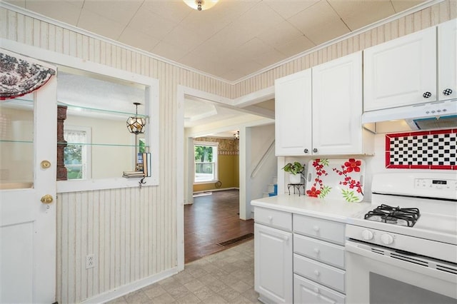 kitchen with gas range gas stove, crown molding, light floors, under cabinet range hood, and white cabinetry